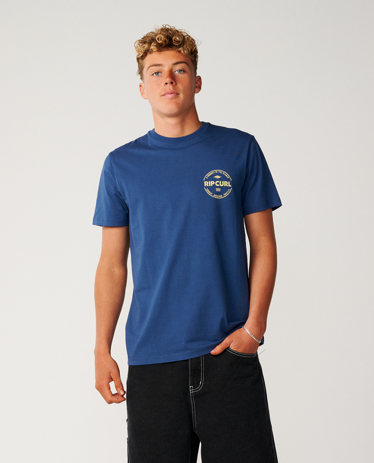blue short-sleeve t-shirt with a circular gold and white 'RIP CURL' logo on the left chest