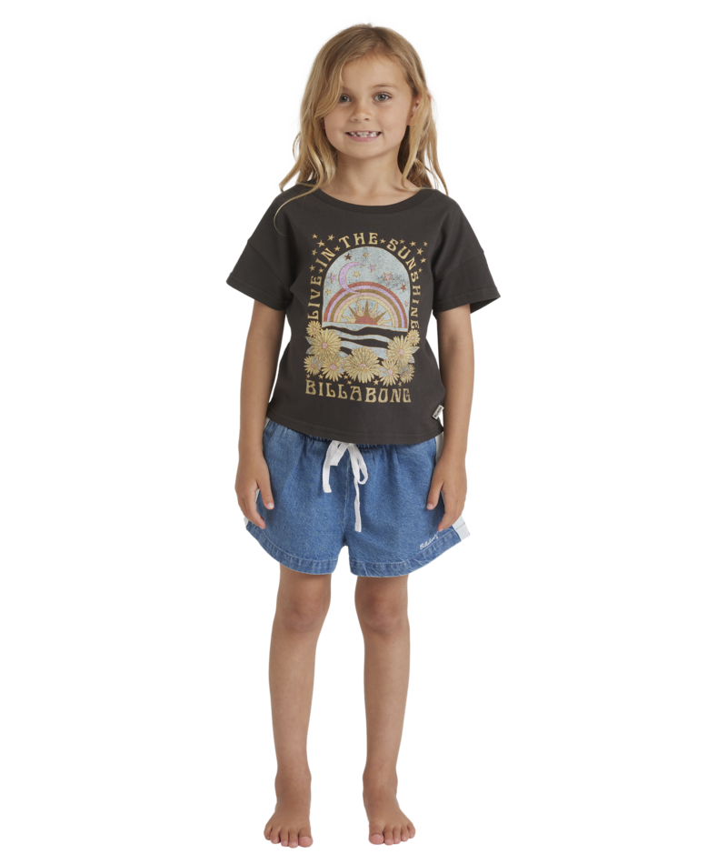 Young girl wearing a black t-shirt with a graphic design and denim shorts on a white background