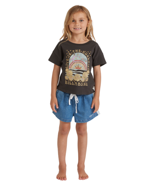 Young girl wearing a black t-shirt with a graphic design and denim shorts on a white background